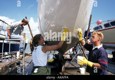 Polissage de la coque d'un Yacht de Cowes, île de Wight, Angleterre Royaume-uni Grande-Bretagne Banque D'Images