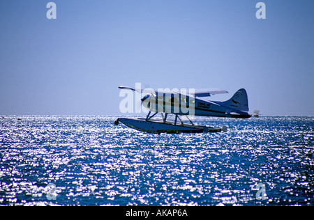 Avion volant à basse altitude au-dessus de la mer de rétroéclairage de la mer Banque D'Images