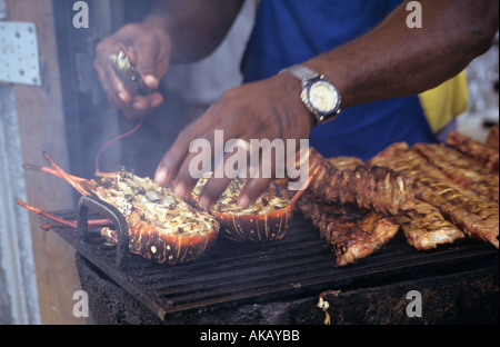 L'homard cuit sur un barbecue avec des armes légères et de cuisiniers dans la fumée des Caraïbes Anguilla Banque D'Images