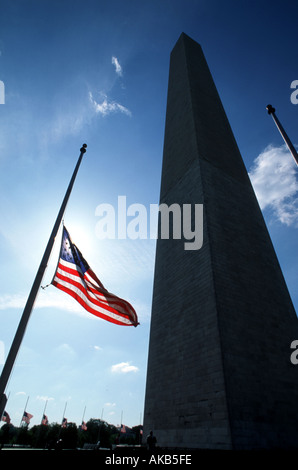 Le rouge blanc et bleu du drapeau américain en berne se bloque sur un poste en face d'un obélisque Memorial à Washington D C Banque D'Images