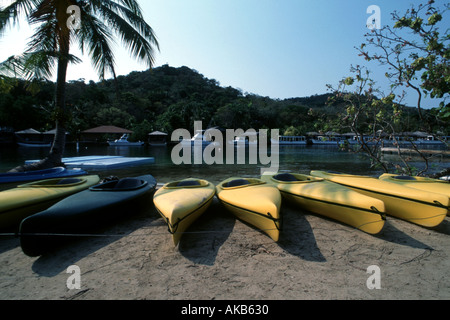 L'équipement de sport d'eau alignés sur un rivage complexe à Roatan Bay Islands Honduras telles que la ligne de kayaks aux couleurs vives Banque D'Images