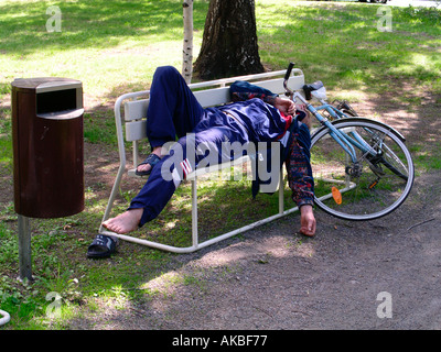 Homme ivre dormir sur banc de parc Banque D'Images