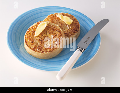 Les crumpets anglais traditionnel et du beurre sur une plaque bleue editorial confort alimentaire Banque D'Images