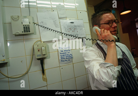 Chef Fergus Henderson arrêtés produits alimentaires à de sa cuisine son téléphone au restaurant St John, Clerkenwell Londres Banque D'Images