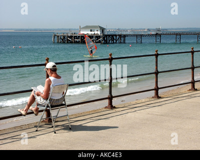 Île de Wight femme lisant un livre sur la promenade à Totland Bay Banque D'Images