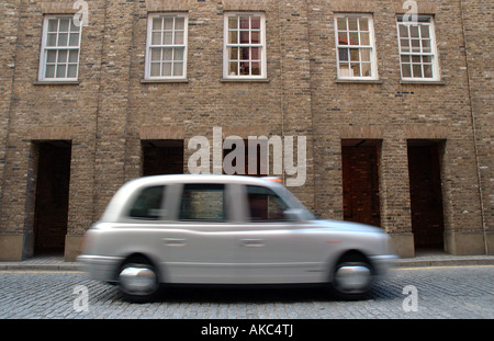 Une icône de Londres, une licence de taxi d'argent se précipiter dans les rues pavées de Wapping Banque D'Images