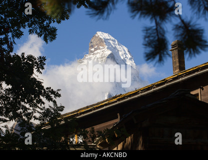 Pic de Mont Cervin encadré de branches de sapins et toit chalet avec cheminée vu de Zermatt Valais Suisse Banque D'Images