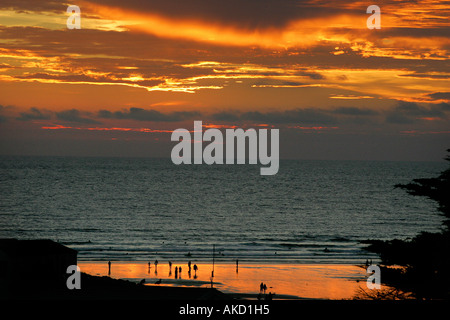 Surfeurs de la plage de Polzeath Cornwall England UK au superbe coucher de soleil colorés Banque D'Images