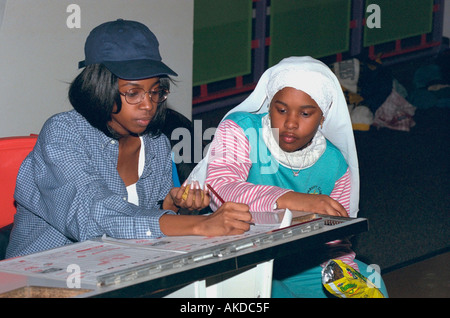 Image main de femme musulmane dans une burqa et ami noir age 14 inscription bowling scores au youth sortie de groupe. Minneapolis Minnesota USA Banque D'Images