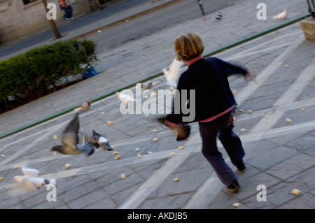 Espagne Andalousie Séville petite fille qui court après les pigeons dans une place publique Banque D'Images