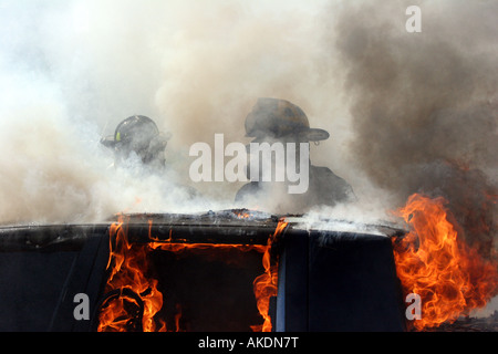 Deux pompiers au milieu de la fumée et de la vapeur au cours de l'extinction d'un incendie dans un scène d'urgence Banque D'Images
