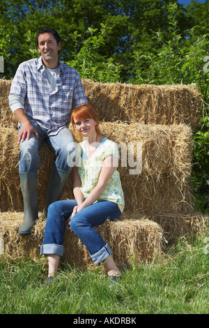 Couple sitting on hay bales in campagne, portrait Banque D'Images