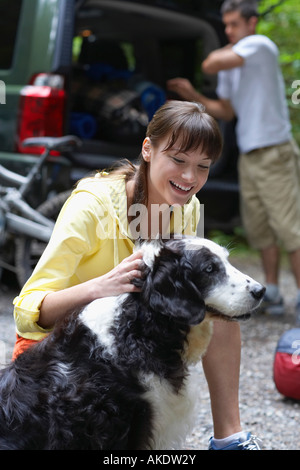 Femme avec chien, l'homme voiture chargement en arrière-plan Banque D'Images