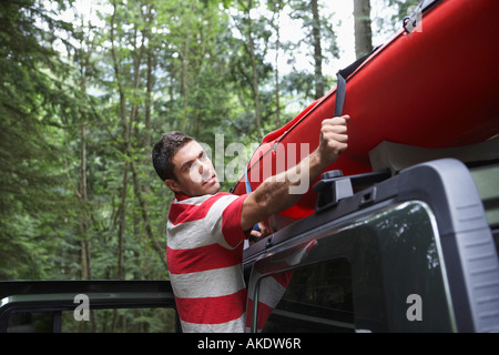 Lier l'homme kayak sur toit de voiture, en forêt Banque D'Images