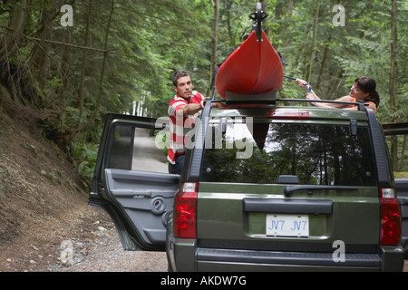 Lier l'homme kayak sur toit de voiture, en forêt Banque D'Images