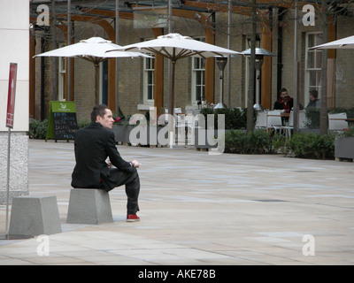 Un homme en costume dans la vingtaine prend une pause du bureau près de Slaone Square Londres Banque D'Images