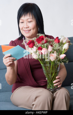 Mature Woman holding de vase et la lecture d'une carte de souhaits Banque D'Images