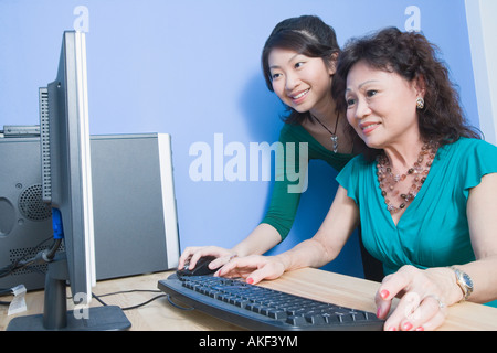 Portrait of a senior woman à l'aide d'un ordinateur avec sa fille debout à côté de sa Banque D'Images