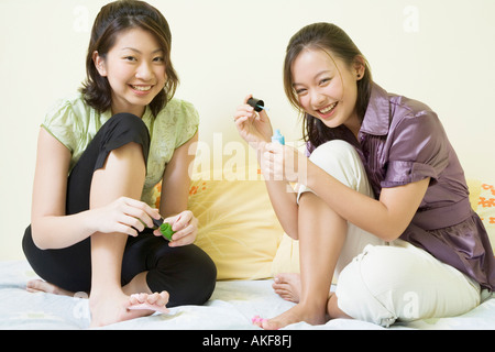 Portrait de deux jeunes femmes, l'application de vernis à ongles sur leurs orteils Banque D'Images