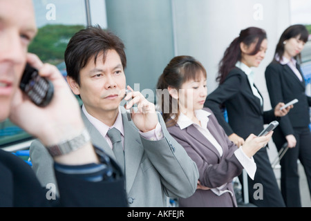 Trois businesswomen avec deux hommes d'attente dans un bar d'aéroport Banque D'Images