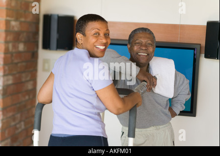 Les Seniors Américains africains exerçant sur la machine pas-à-pas et une télévision à écran plasma Banque D'Images