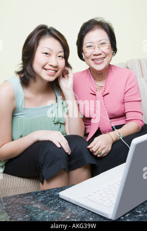 Portrait of a senior woman avec sa petite-fille assis sur un canapé en face d'un ordinateur portable Banque D'Images