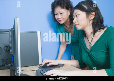 Portrait d'une jeune femme à l'aide d'un ordinateur avec sa mère debout à côté de sa Banque D'Images