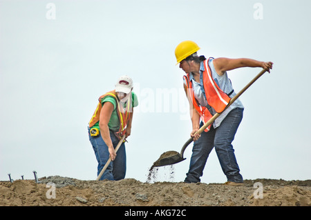 Chantier de construction routière, avec les jeunes femmes qui travaillent fort à la pelle Banque D'Images