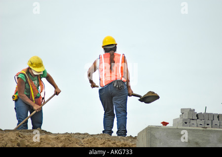 Chantier de construction routière, avec les jeunes femmes qui travaillent fort à la pelle Banque D'Images