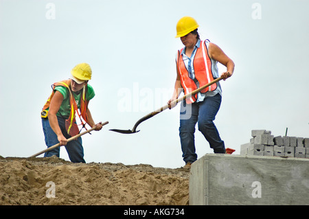 Chantier de construction routière, avec les jeunes femmes qui travaillent fort à la pelle Banque D'Images