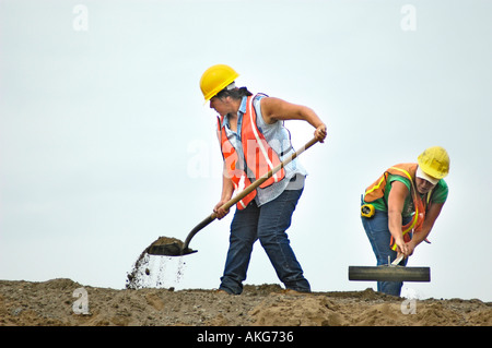 Chantier de construction routière, avec les jeunes femmes qui travaillent fort à la pelle Banque D'Images