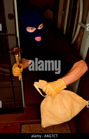 Un cambrioleur de voler une maison portant une cagoule. Banque D'Images