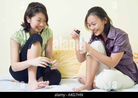 Deux jeunes femmes l'application de vernis à ongles sur leurs orteils Banque D'Images