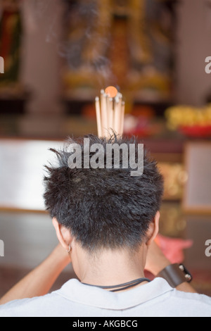 Vue arrière d'un jeune homme qui prie dans un temple Banque D'Images