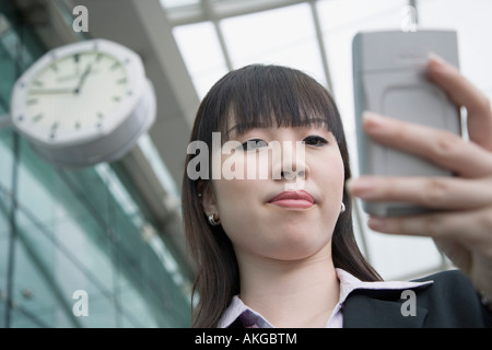 Low angle view of a young à l'aide d'un palmtop et l'attente dans un bar d'aéroport Banque D'Images