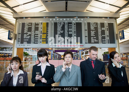 Cinq cadres d'affaires debout devant une arrivée départ chambre dans un aéroport Banque D'Images
