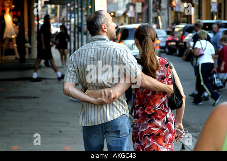 Un couple se promener le long d'une rue animée de la Nouvelle Orléans avec leurs bras enlacés Banque D'Images