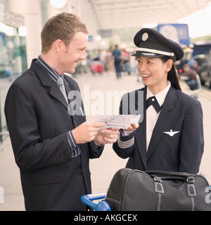 D'affaires et une femme pilote looking at each other and smiling Banque D'Images