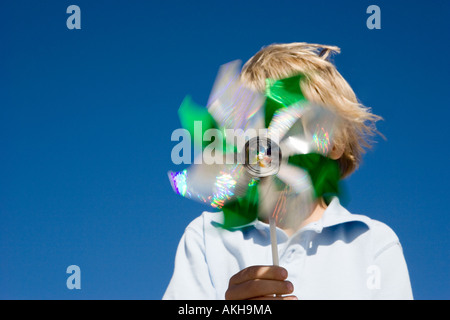 Boy holding pinwheel en face de visage Banque D'Images