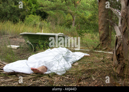 Pied de corps mort femme de race blanche qui dépasse de sous Feuille blanche en Caroline du Sud USA Marais, scène du crime Banque D'Images