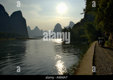 Lijiang ou Rivière Li au coucher du soleil avec l'homme en tricycle sur la route - Yangshuo County, Guangxi, Chine Banque D'Images
