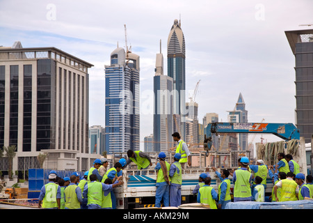 Ouvriers asiatiques sur place à l'inachevé, incomplet ; bâtiments gratte-ciel projet de construction étrangers immigrant workers building le nouveau Dubaï. Émirats arabes unis Banque D'Images