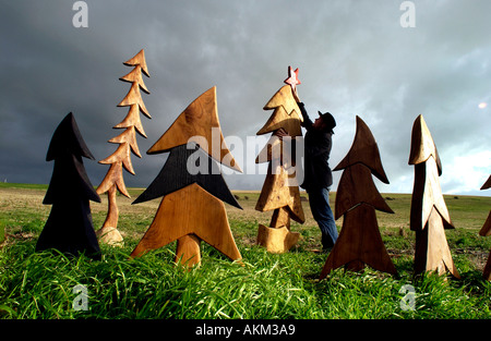 Artiste Johnny Woodford mettre une étoile sur l'un de ses arbres de Noël en bois surréaliste faite de bois de l'Orme recyclé. Banque D'Images