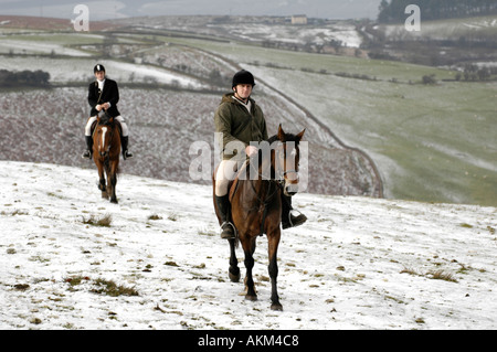 Adeptes de chasse à cheval à la poursuite d'Llangeinor Hunt sur colline au-dessus de la neige près de Bridgend Blackmill South Wales UK Banque D'Images