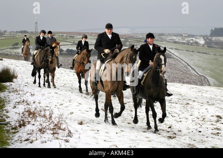 Adeptes de chasse à cheval à la poursuite d'Llangeinor Hunt sur colline au-dessus de la neige près de Bridgend Blackmill South Wales UK Banque D'Images