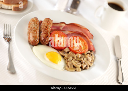 TABLE DU PETIT DÉJEUNER avec petit déjeuner anglais cuisiné traditionnel FRITES FRIED EGG BACON SAUCISSE CHAMPIGNONS ET Tomates frites avec café Banque D'Images