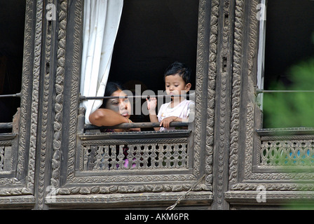 La mère et l'enfant à la recherche d'une fenêtre richement sculpté dans la région de Katmandou Népal Patan Banque D'Images
