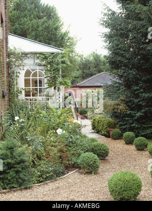 Boules topiaires taillés de chemin de gravier de chant conservatoire de country house Jardin avec arbustes en massifs Banque D'Images