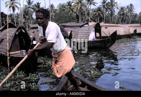 Boatman poling un bateau de riz sur les Backwaters du Kerala State près de Chennai en Inde du Sud Banque D'Images