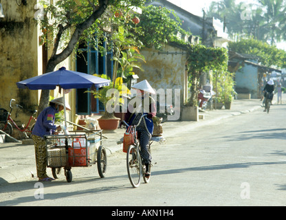 Vendeur de rue et cycliste de St Bach Dang, tôt le matin, Hoi An, Viet Nam Banque D'Images